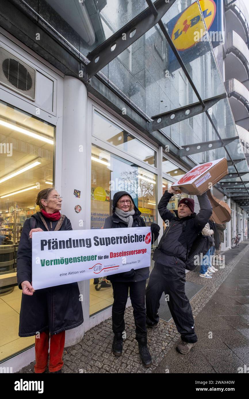 Symbolische Pfändungen von Superreichen Deutschland, Berlin, 21.12.2023, Aktion von Gemeingut in BürgerInnenhand giB, Aktionen vor Filialen von LIDL, Aldi und BMW, hier eine Lidl Filiale in der Luisenstraße / Berlin-Mitte, Aktivisten drücken ein großes Pfandsiegel auf eine Tür der LIDL-Filiale, Carl Waßmuth re., Sprecher von Gemeingut: Superreiche wie LIDL-Eigentümer Dieter Schwarz zahlen nur winzige Steuersätze, Â *** symbolische Beschlagnahmen des superreichen Deutschland, Berlin, 21 12 2023, Aktion Gemeingut in BürgerInnenhand giB , Aktionen vor Zweigen von LIDL, Aldi und BMW, hier eine Lidl-Niederlassung Stockfoto