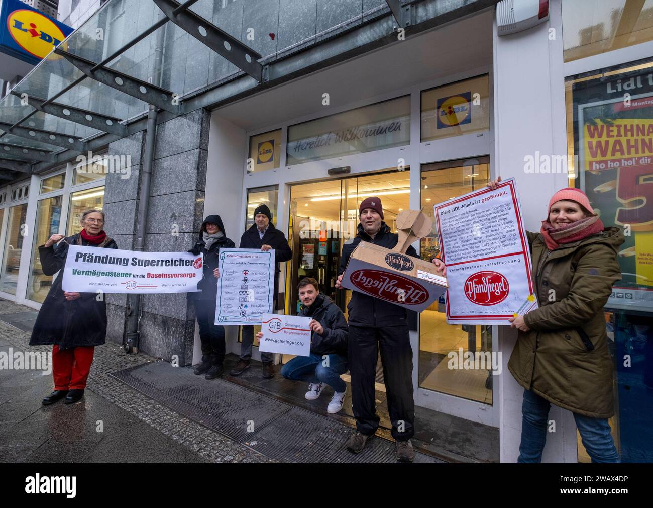 Symbolische Pfändungen von Superreichen Deutschland, Berlin, 21.12.2023, Aktion von Gemeingut in BürgerInnenhand giB, Aktionen vor Filialen von LIDL, Aldi und BMW, hier eine Lidl Filiale in der Luisenstraße / Berlin-Mitte, Aktivisten drücken ein großes Pfandsiegel auf eine Tür der Lidl-Filiale, Carl Waßmuth, Sprecher von Gemeingut: Superreiche wie LIDL-Eigentümer Dieter Schwarz zahlen nur winzige Steuersätze, Â *** symbolische Beschlagnahmen des superreichen Deutschland, Berlin, 21 12 2023, Aktion Gemeingut in BürgerInnenhand giB , Aktionen vor Zweigen von LIDL, Aldi und BMW, hier eine Lidl-Niederlassung in L Stockfoto