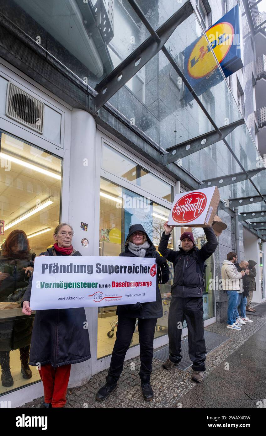 Symbolische Pfändungen von Superreichen Deutschland, Berlin, 21.12.2023, Aktion von Gemeingut in BürgerInnenhand giB, Aktionen vor Filialen von LIDL, Aldi und BMW, hier eine Lidl Filiale in der Luisenstraße / Berlin-Mitte, Aktivisten drücken ein großes Pfandsiegel auf eine Tür der LIDL-Filiale, Carl Waßmuth re., Sprecher von Gemeingut: Superreiche wie LIDL-Eigentümer Dieter Schwarz zahlen nur winzige Steuersätze, Â *** symbolische Beschlagnahmen des superreichen Deutschland, Berlin, 21 12 2023, Aktion Gemeingut in BürgerInnenhand giB , Aktionen vor Zweigen von LIDL, Aldi und BMW, hier eine Lidl-Niederlassung Stockfoto