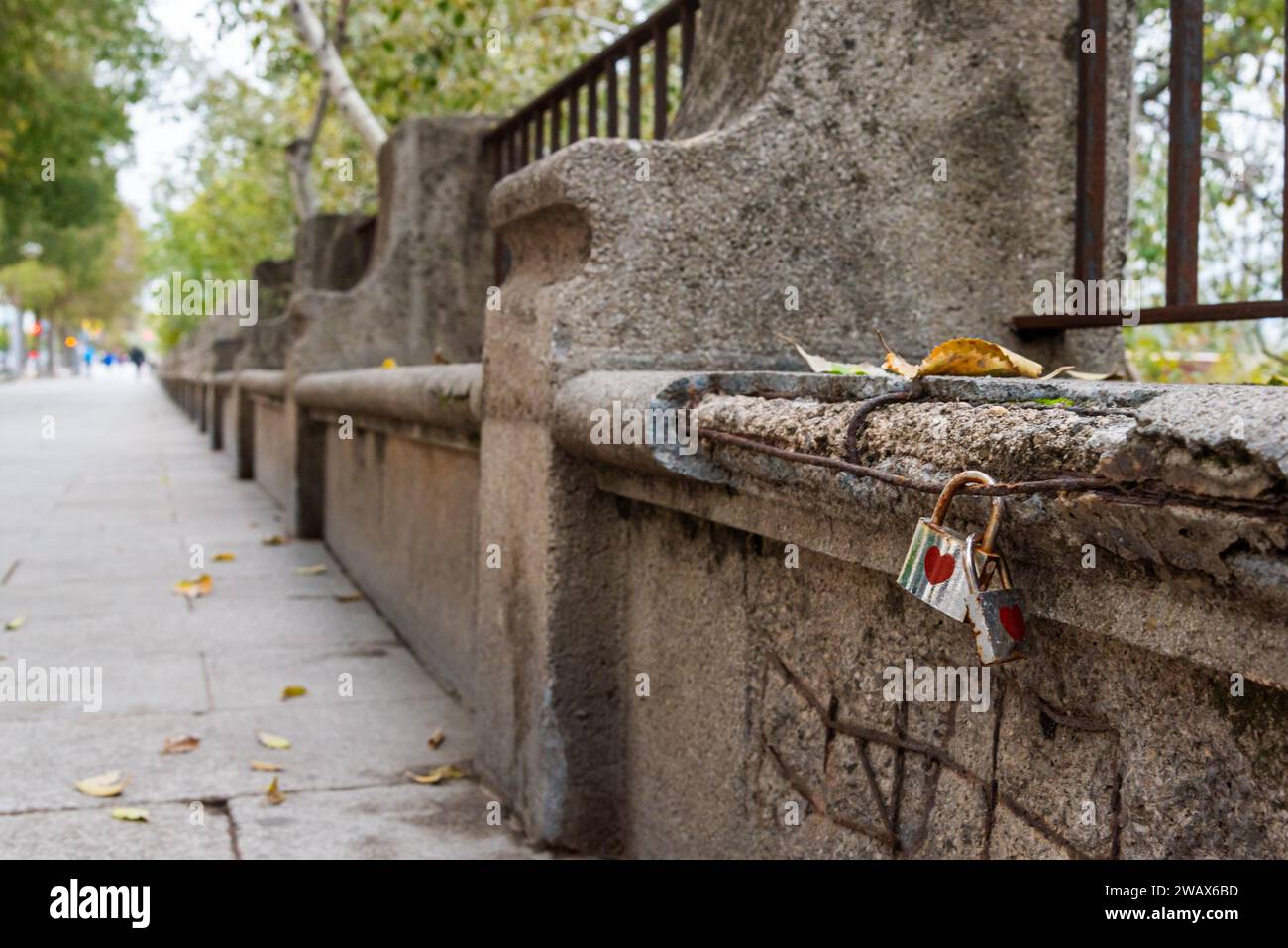 Zwei Vorhängeschlösser, die aneinander gehakt sind, und an einer Bank mit dem Herzsymbol auf dem Paseo de la Ribera in Cordoba. Stockfoto