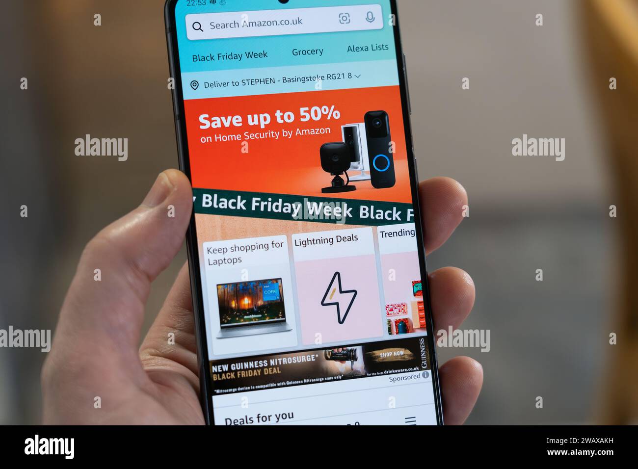 Black Friday Week mit Werbebanner und Seite aus der Amazon Shopping App auf einem Smartphone, das von einer Hand gehalten wird, UK Stockfoto