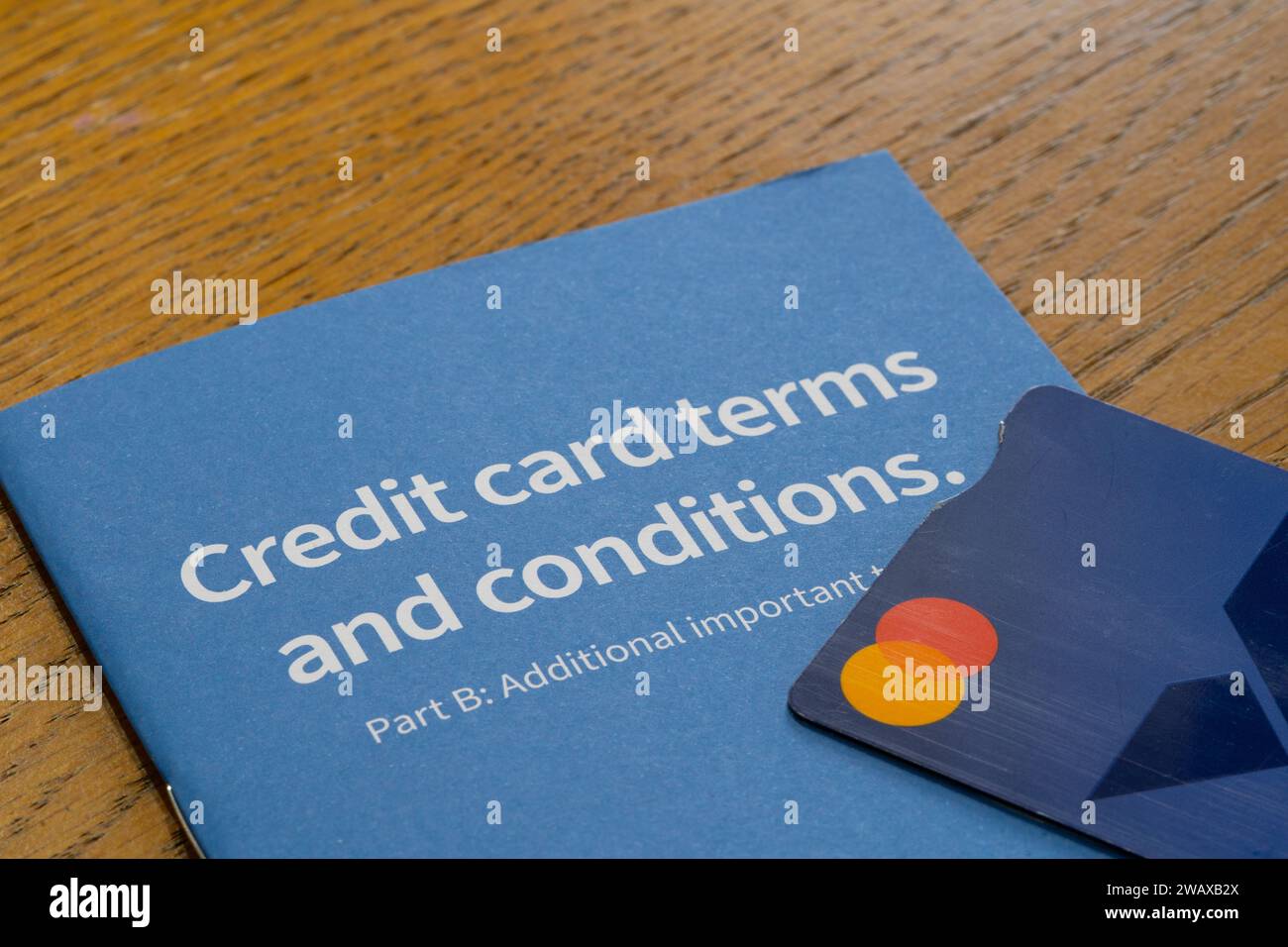 Eine Broschüre mit den Geschäftsbedingungen für Halifax-Kreditkarten, auf der eine Kreditkarte angebracht ist. Thema: Britische Kreditkartenschulden, britische Verbraucherschulden, Kreditkartenrückzahlungen Stockfoto