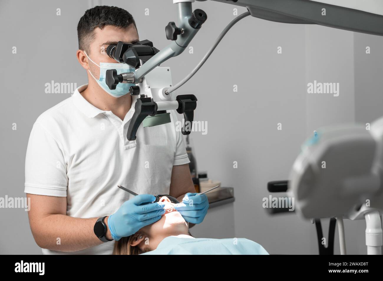 Ein akribischer und hochqualifizierter Zahnarzt untersucht den Zahn jedes Patienten sorgfältig unter einem Mikroskop, um Zahnprobleme zu identifizieren und zu lösen Stockfoto