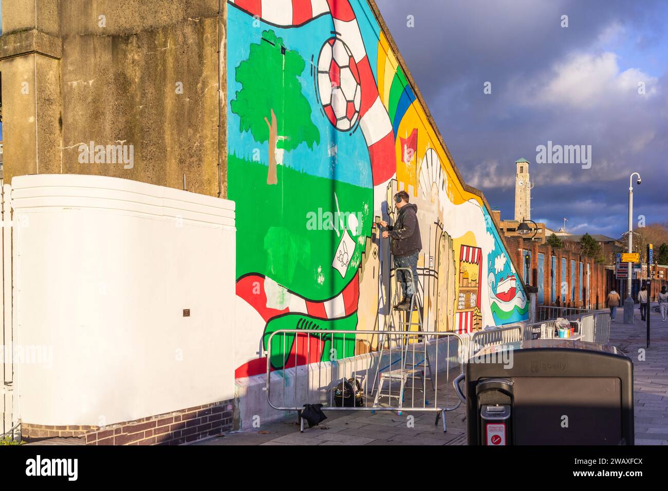 Southampton, Großbritannien. 6. Januar 2024. Ein Künstler malte ein farbenfrohes, lebendiges Wandbild an der Wand der Treppe auf der Südseite der Southampton Central Station South Side, als Teil des kürzlich durchgeführten Sanierungsprojekts des Southampton Central Train Station. Dieses Projekt wurde vom Transforming Cities Fund der Regierung finanziert und von Network Rail und South Western Railway unterstützt. Das Kunstwerk zeigt Höhepunkte der Stadt Southampton. Das Design wurde vom lokalen Künstler Poppy Ash entworfen. Stockfoto