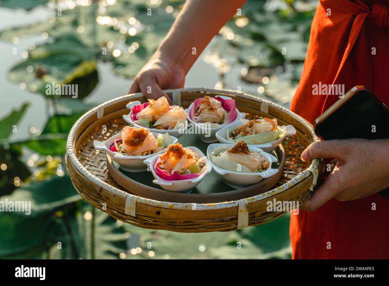 Traditioneller thailändischer Snack namens Miang Kham, pikant rosa Lotusblüten verpackt (pikante Lotusblüten-Wraps). Köstliches Frisches Lotusblüten-Bohnenkraut Stockfoto