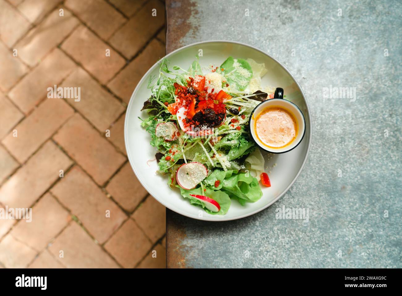 Frischer grüner veganer Salat aus grünen Blättern und Gemüse. Draufsicht auf grauem Steintisch. Griechischer Salat mit frischer Gurke, Tomate, süßem Pfeffer, Lettu Stockfoto