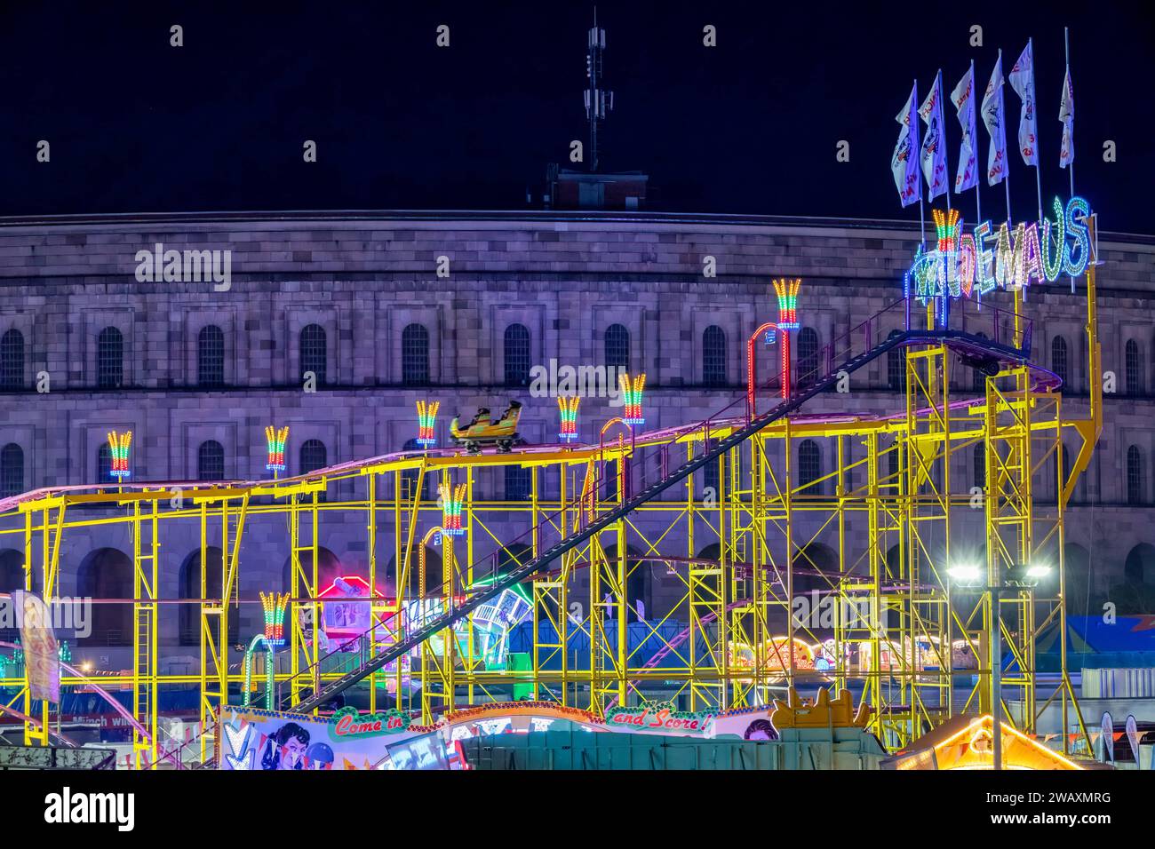 Nürnberger Volksfest bei Nacht das Fahrgeschäft Wilde Maus auf dem Nürberger Volksfest mit dem Volksfest beleuchteten Front der Kongresshalle. Nürnberg Bayern Deutschland *** Nürnberger Volksfest bei Nacht die wilde Maus Fahrt beim Nürnberger Volksfest mit der Vorderseite der Nürnberger Kongresshalle beleuchtet vom Volksfest Bavaria Germany 20230421-6V2A7309-Bearbeitet Stockfoto