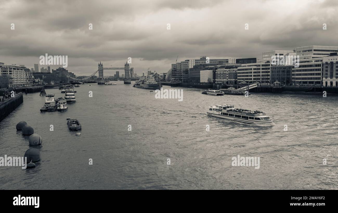 Ein Fernblick auf die Tower Bridge im Hintergrund, während ein Touristenboot in London, England, die Themse entlang fährt Stockfoto