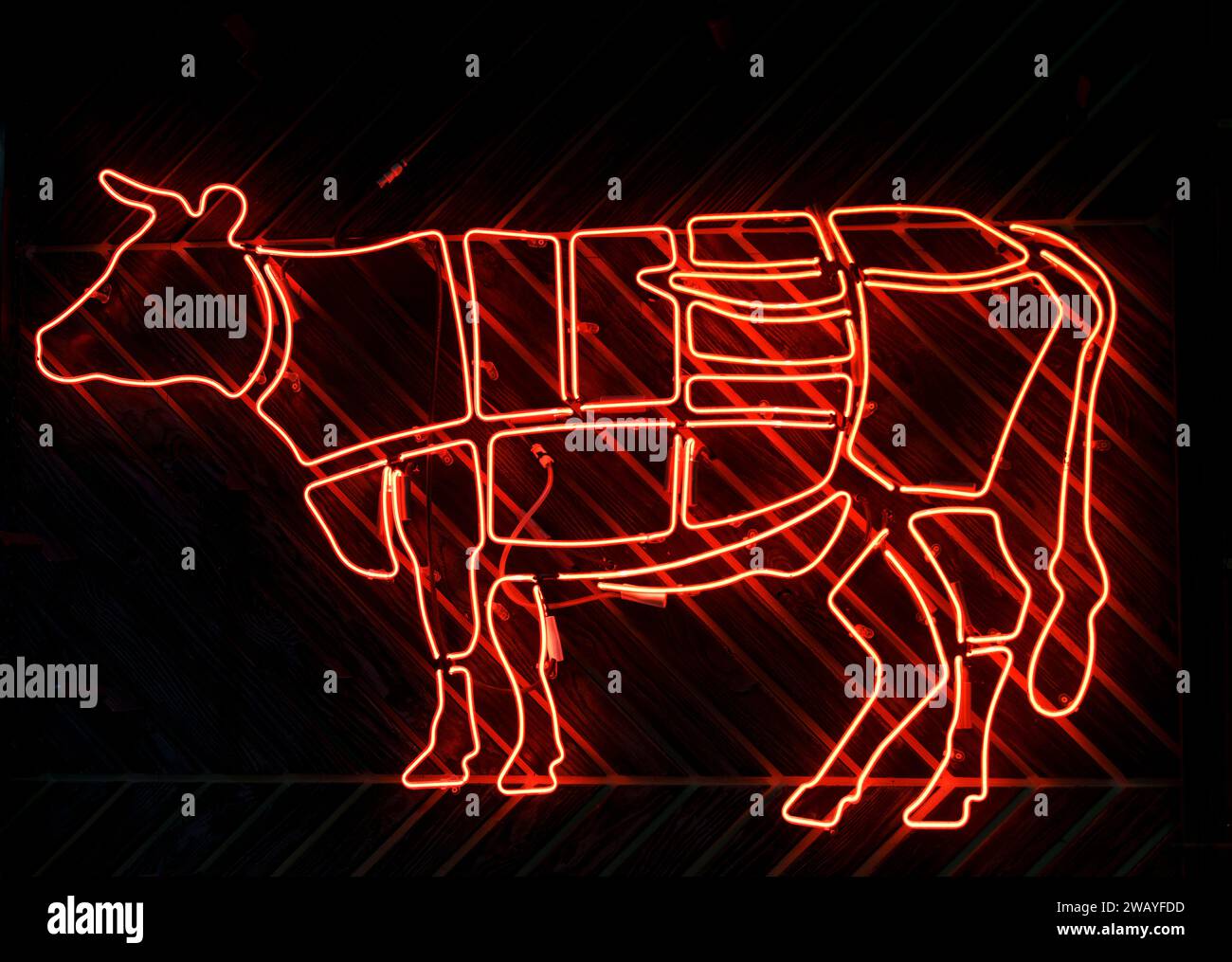 Neon-Zeichen einer Kuh, die Rindfleisch in Fleischteile zerschneidet. Hochwertige Fotos Stockfoto