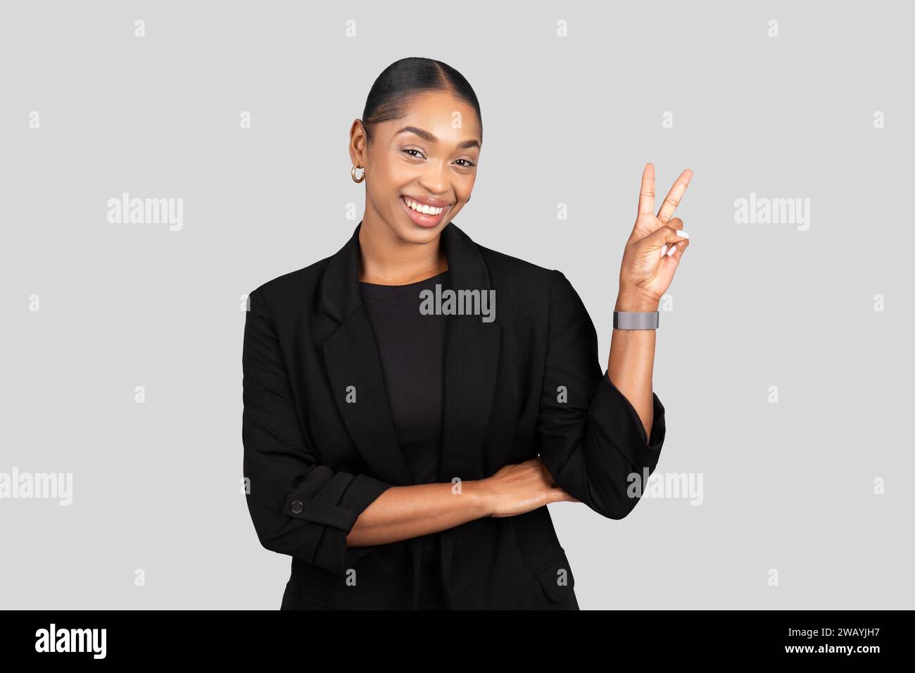 Charmante afroamerikanische Geschäftsfrau mit einem freundlichen Lächeln ist ein Friedenszeichen Stockfoto