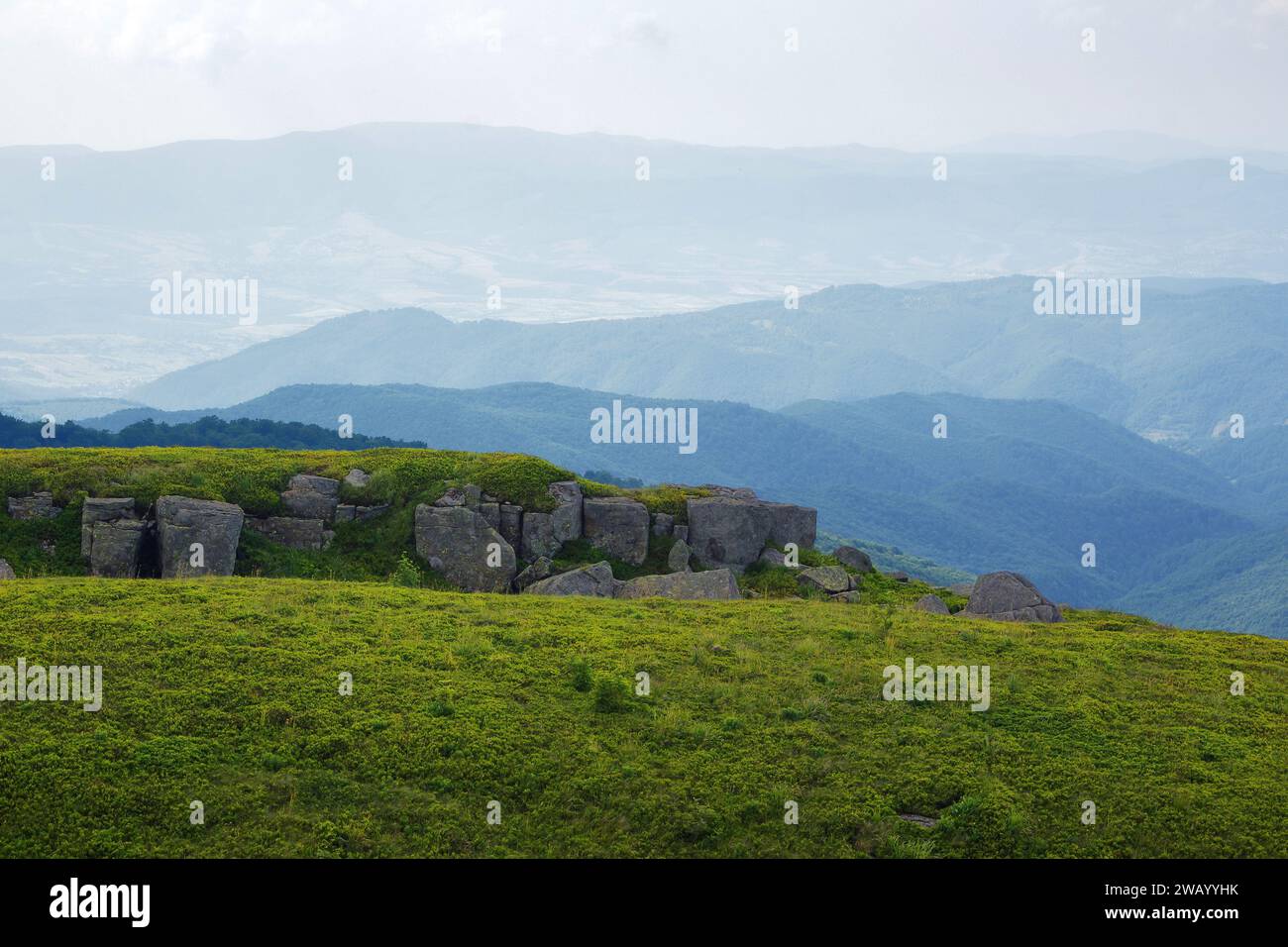 Felsbrocken auf dem grasbewachsenen Hügel. Berglandschaft im Sommer. Wolken am Himmel Stockfoto