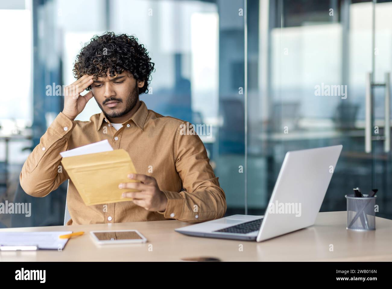 Trauriger unzufriedener und unglücklicher Geschäftsmann im Büro am Arbeitsplatz, Mann erhielt Briefumschlag Fuchs mit Benachrichtigung mit schlechten Nachrichten, Arbeiter liest enttäuscht. Stockfoto