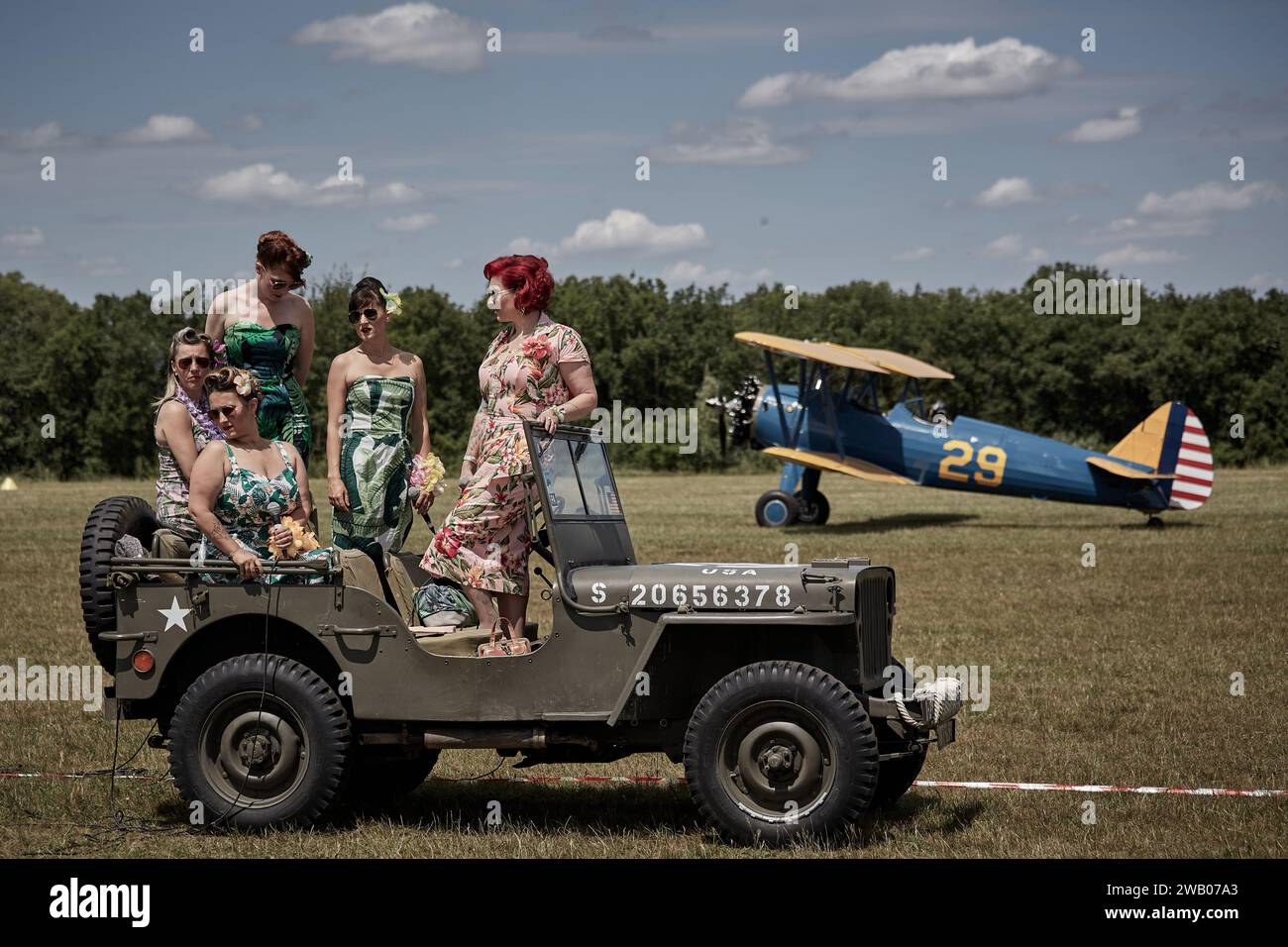 Pin-UPS plaudern auf einem Jeep Willys mit einem blauen und gelben Doppeldecker im Hintergrund Stockfoto