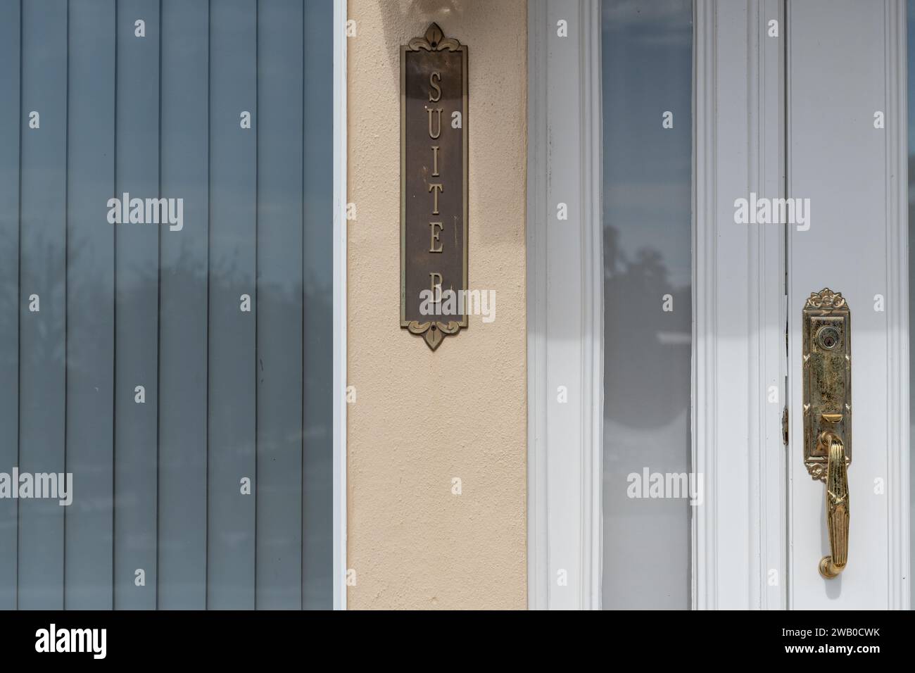 Der Außeneingang eines Luxushotels mit blauer Holzverkleidung. Die Verkleidung ist gelb und weiß. Ein Schild aus Messing zeigt Suite B. Stockfoto Der Außeneingang eines Luxushotels mit blauer Holzverkleidung. Die Verkleidung ist gelb und weiß. Ein Schild aus Messing zeigt Suite B. Stockfoto