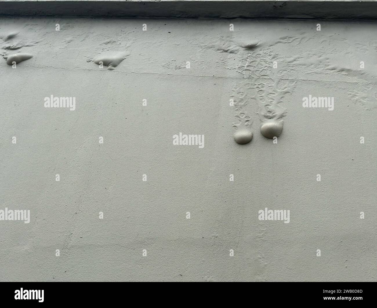 Eine graue Zementaußenwand, die mit einer Textur bemalt ist. Luftblasen oder Feuchtigkeitsblasen laufen durch Wasserschäden an der Wand herunter. Stockfoto