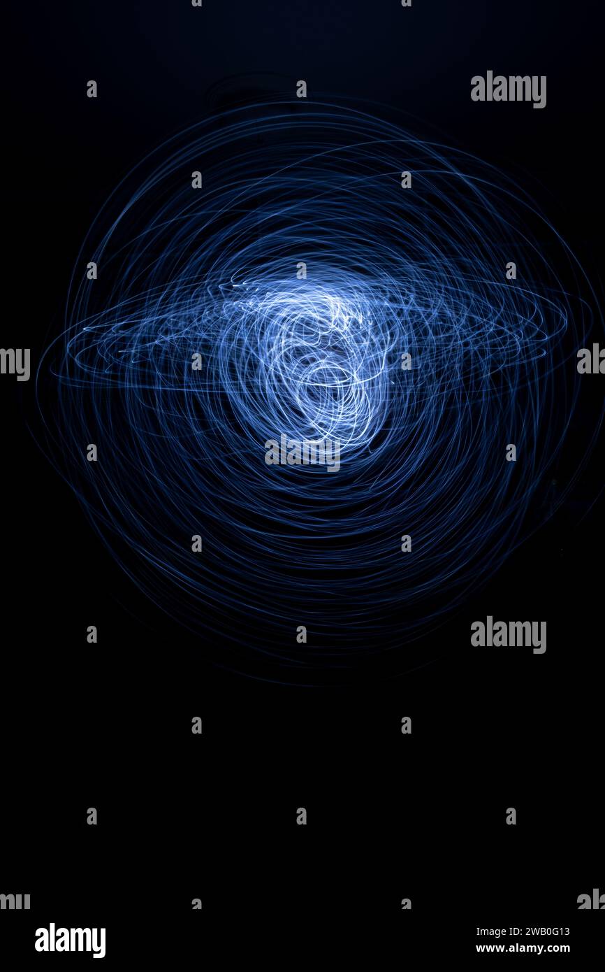 Bei diesem Hintergrund mit langer Belichtung und langsamer Verschlusszeit drehen sich kreisförmige Streifen kühlem Licht um. Stockfoto