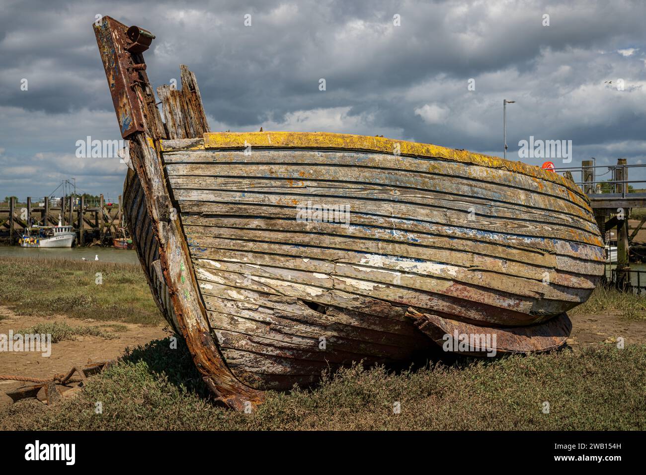 Rye Harbour, East Sussex, England, Vereinigtes Königreich - 12. Mai 2022: Ein altes Schiffswrack und einige Boote am Ufer des Flusses Rother Stockfoto