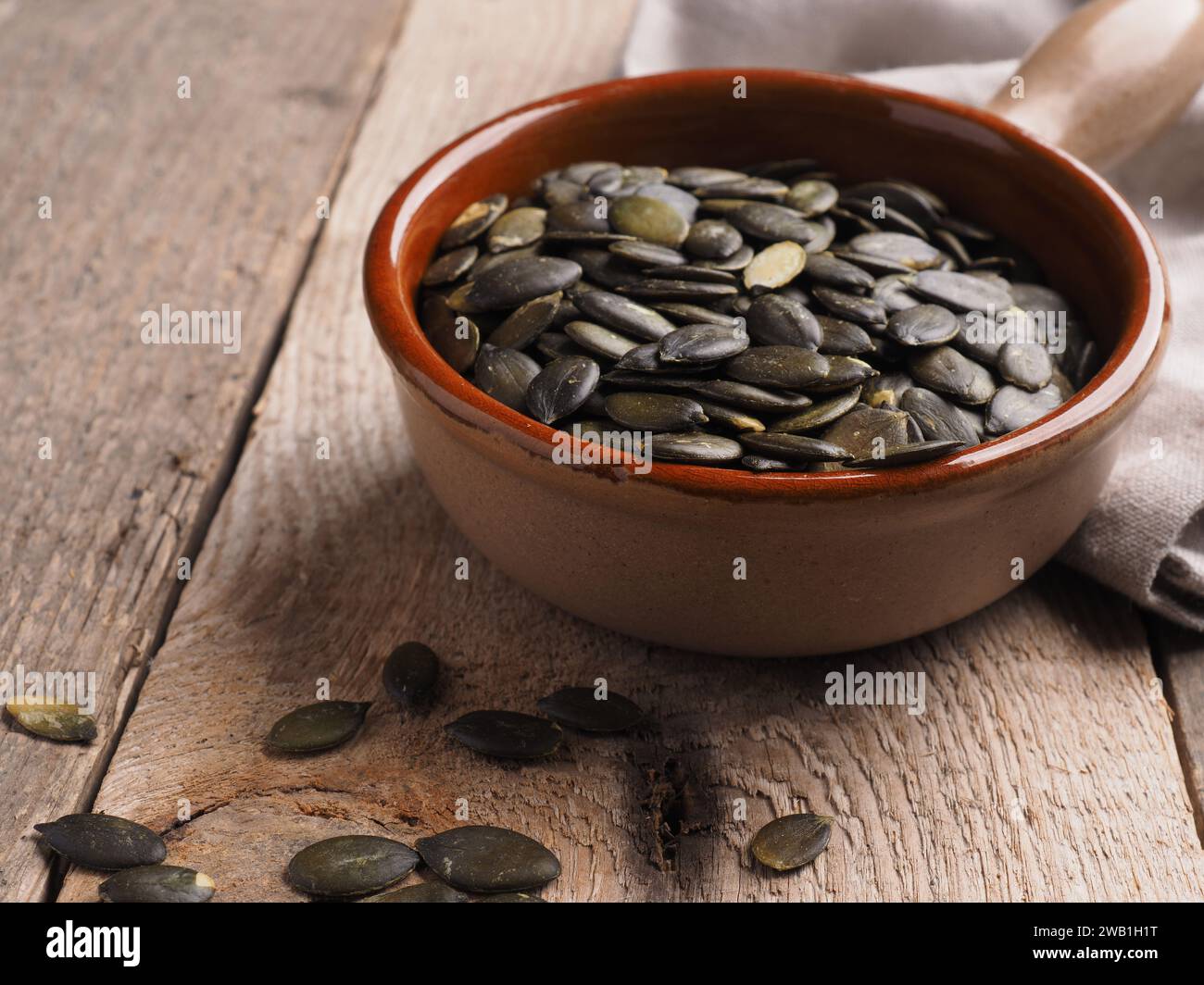 Leckere Bio-Kürbiskerne in einer Keramikschale auf einem hölzernen Küchentisch, gesunde Zutaten oder super-Food-Konzept Stockfoto