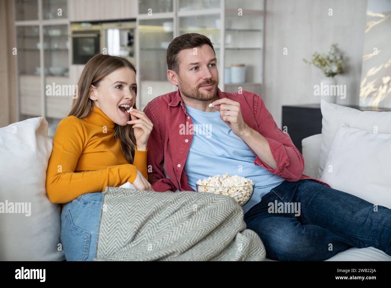 Freunde, Paare, schauen sich lustige Filmkomödie zusammen, sitzen auf der Couch zu Hause und essen Popcorn. Stockfoto