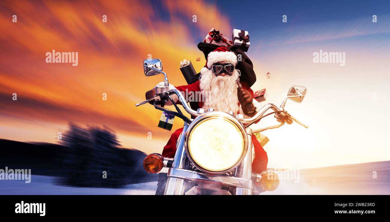 Coole Weihnachtsmann-Biker, die bei Sonnenuntergang mit einem schnellen Motorrad fahren und Weihnachtsgeschenke liefern Stockfoto