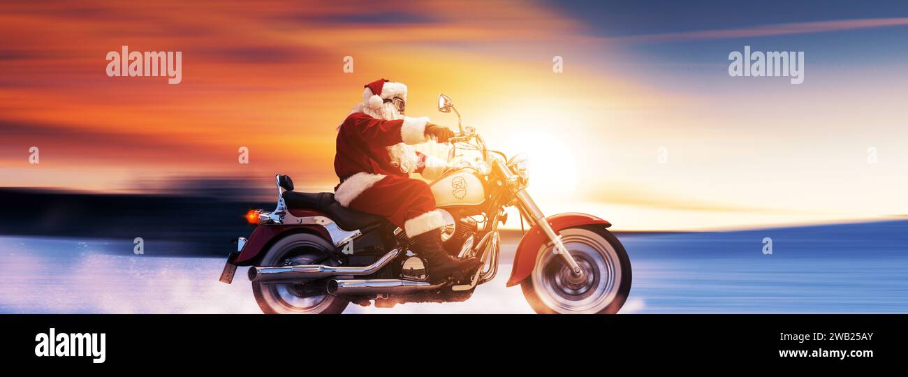 Cooler Weihnachtsmann mit einem schnellen Motorrad bei Sonnenuntergang, unkonventionelles Weihnachtskonzept Stockfoto