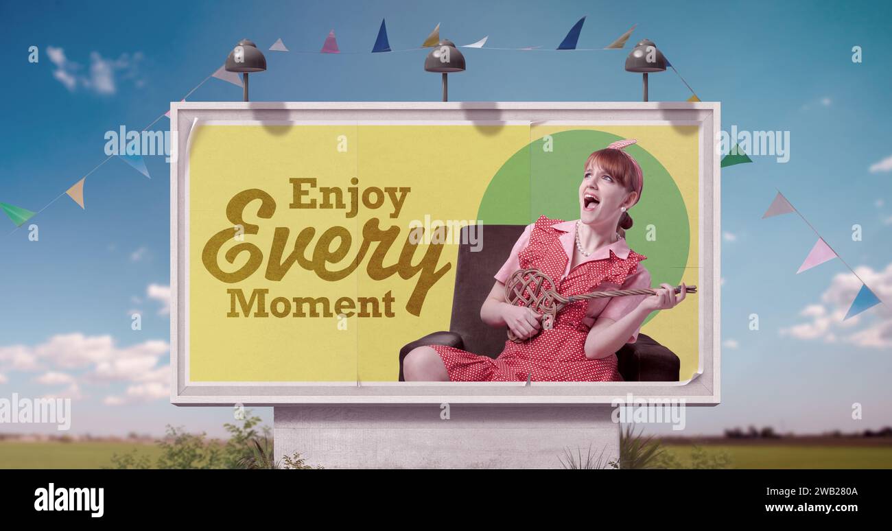 Fröhliche, faule Hausfrau mit Spaß und inspirierendem Zitat auf der Werbetafel: Genießen Sie jeden Moment Stockfoto