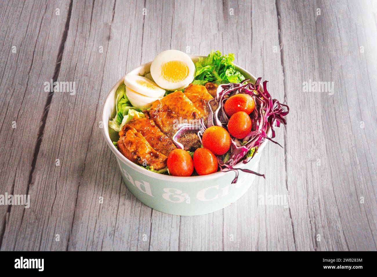 Gegrillte Hähnchenschenkel mit Salat, Rotkohl, Tomaten und hart gekochtem Ei Stockfoto