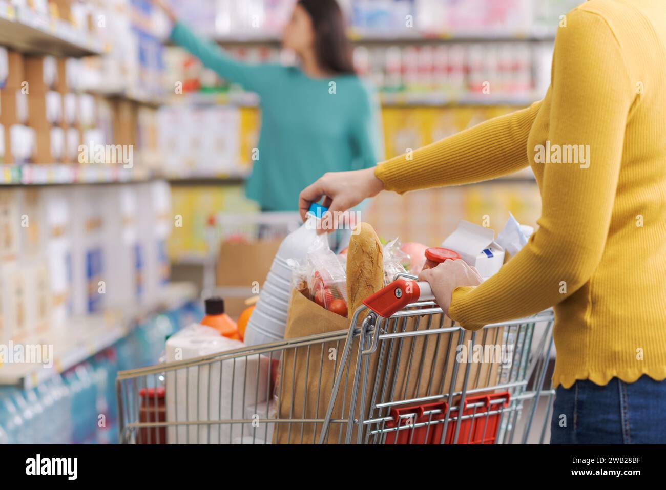 Frau im Lebensmittelgeschäft, sie schiebt einen Einkaufswagen und kauft Produkte Stockfoto