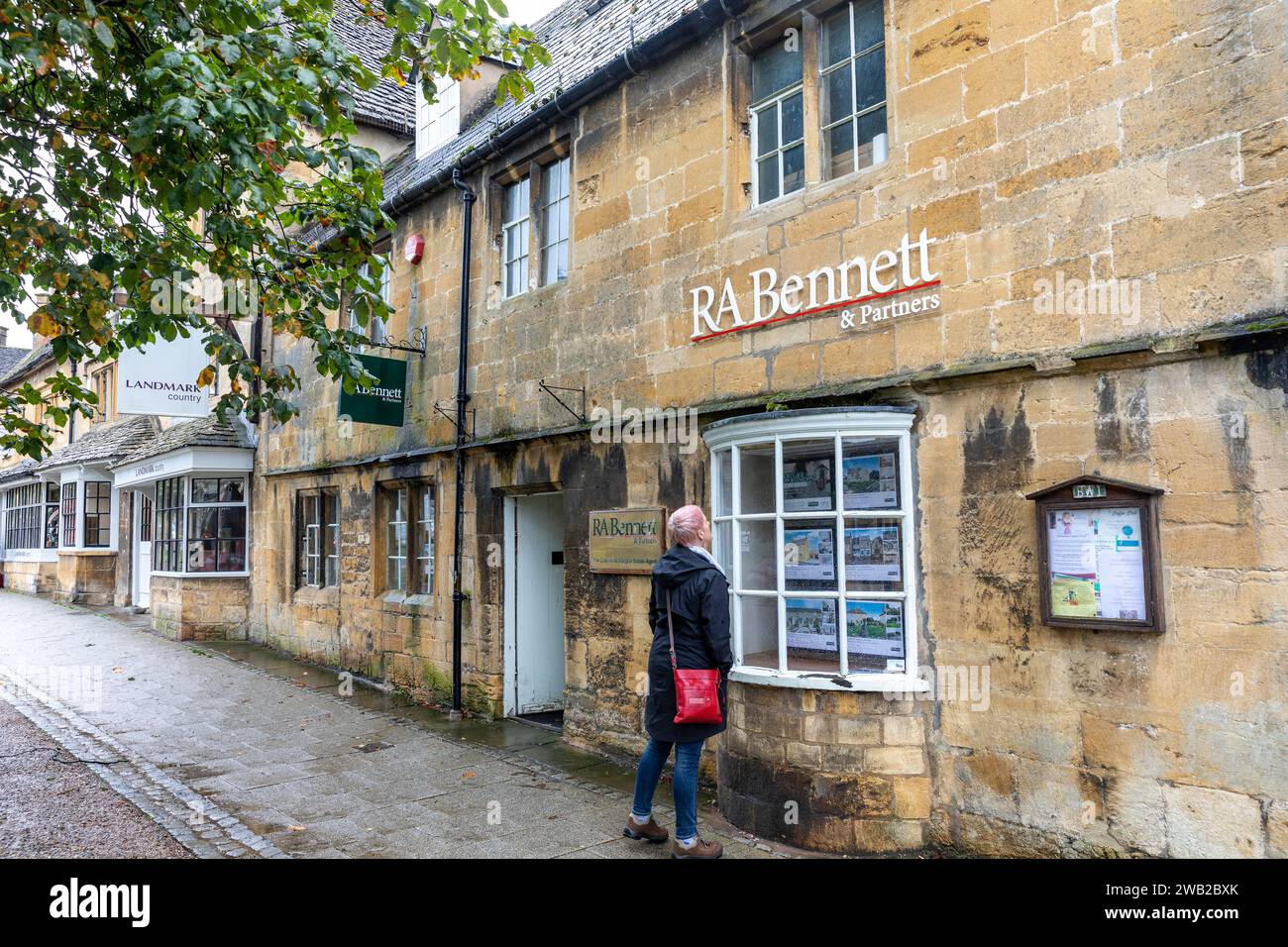 Hausjagd in den cotswolds, Model freigelassene Frau, die Häuser zum Verkauf in Window, England, Großbritannien, 2023 sucht Stockfoto