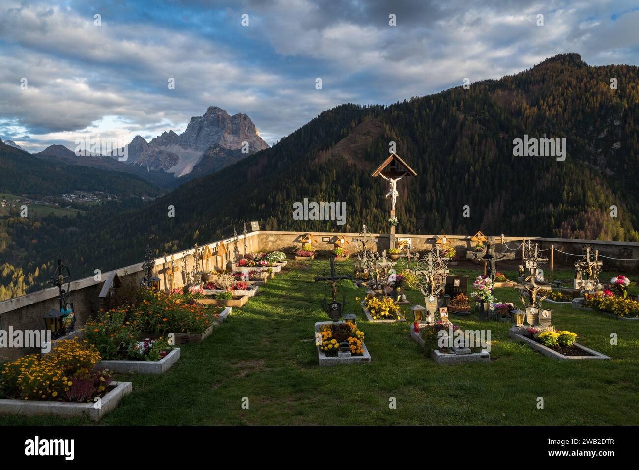 Kirchenfriedhof bei Sonnenuntergang umgeben von Bergen Stockfoto