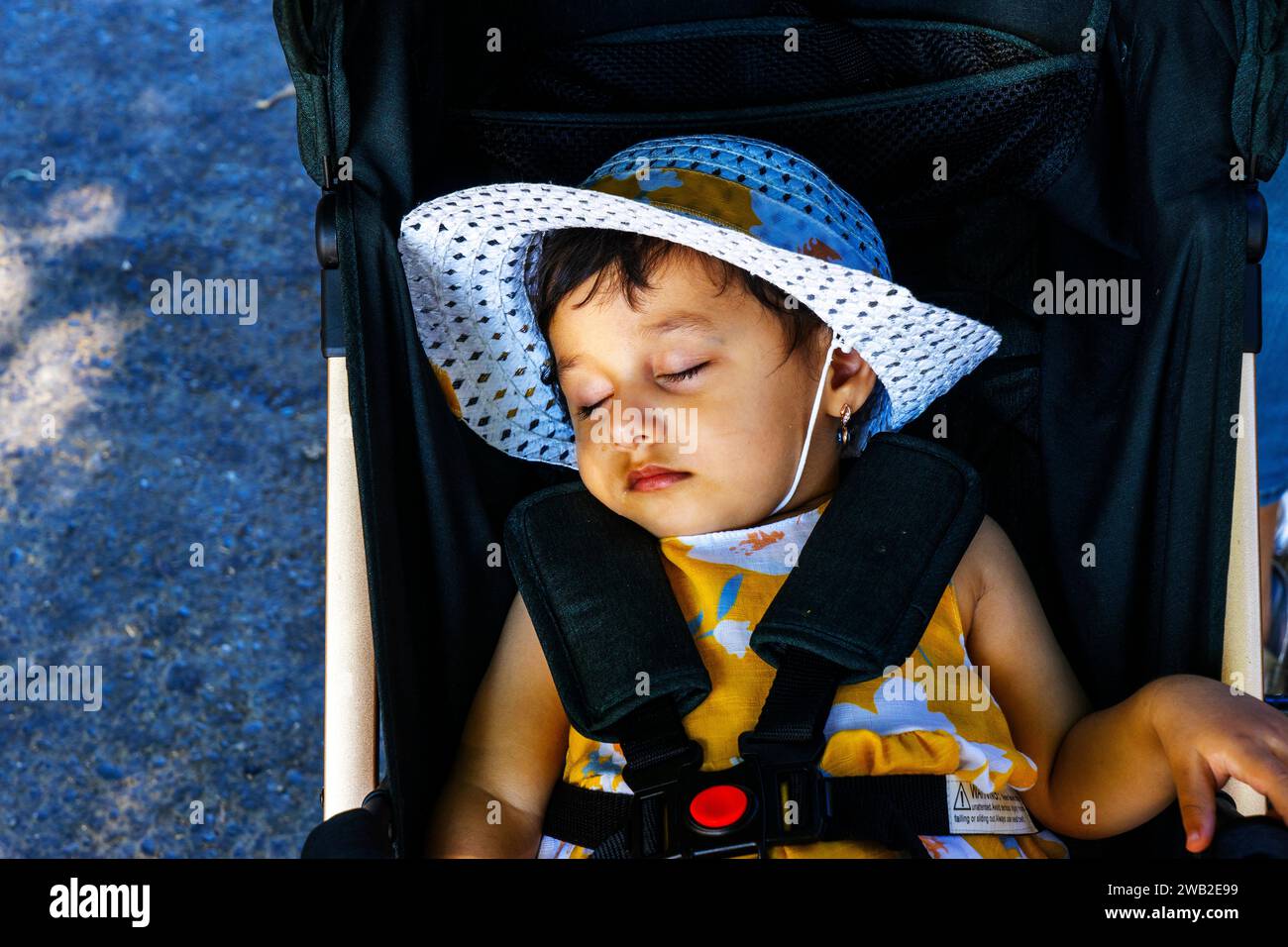 Ein kleines wunderschönes dunkelhäutiges Mädchen schläft in einem Kinderwagen. Stockfoto