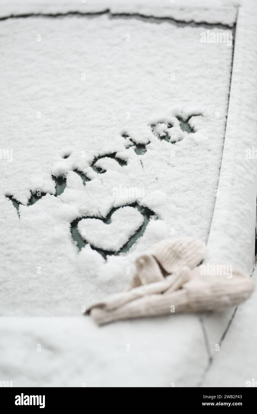 Die Worte „Winter“ und das Herzsymbol im Schnee auf das Autofenster geschrieben Stockfoto
