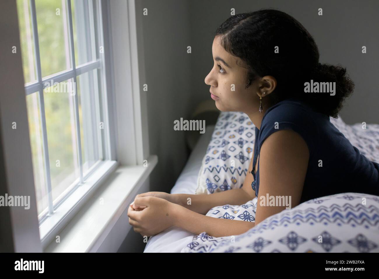 Ein birassisches Teenager-Mädchen sieht deprimiert aus dem Fenster aus Stockfoto