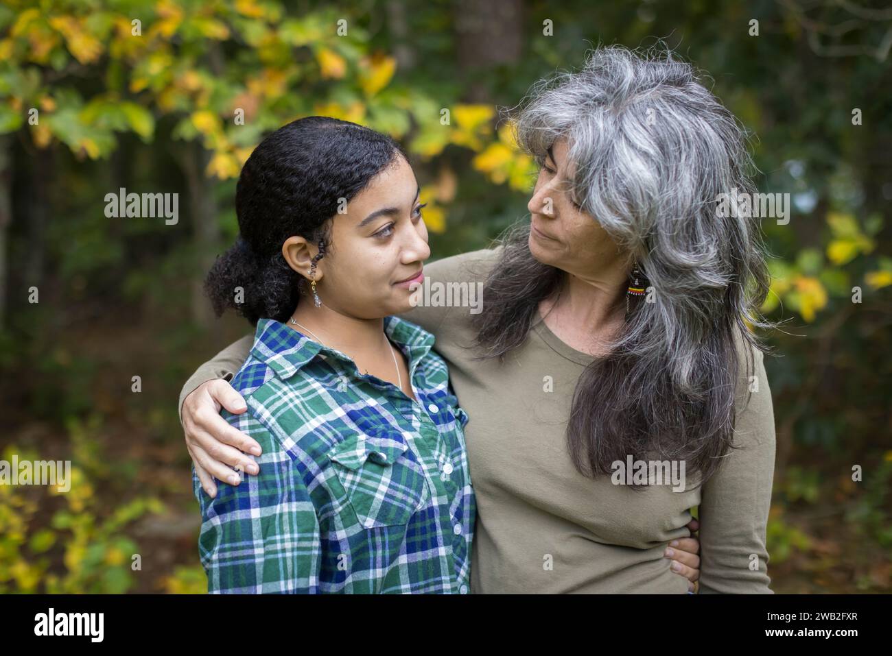 Eine weiße Mutter legt einen Arm um ihre zweirassige Teenager-Tochter Stockfoto