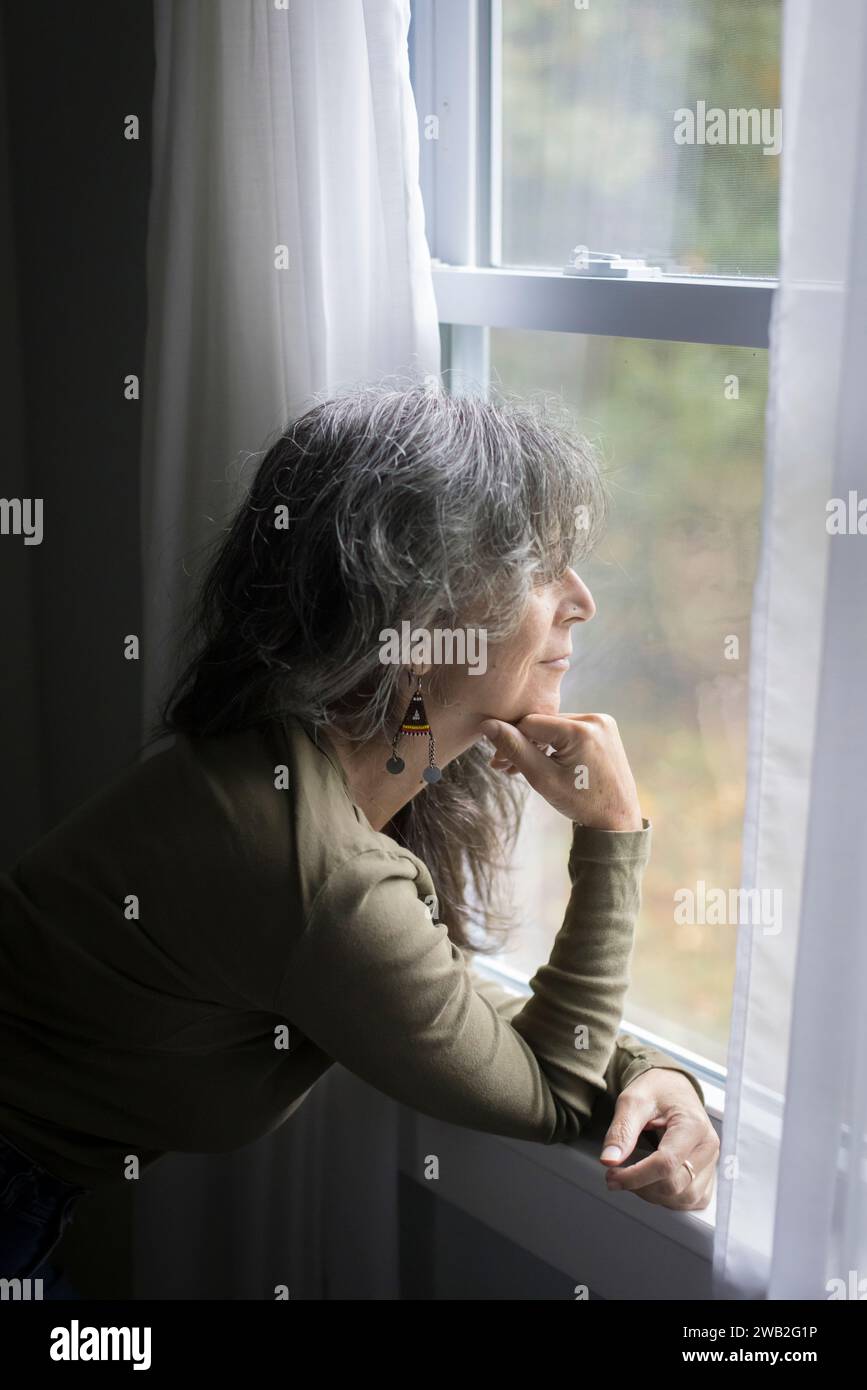 Ältere weiße Frau im Profil schaut aus dem Fenster Stockfoto