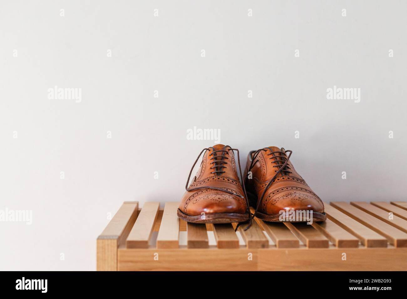 Braune Lederschuhe auf einer Holzbank zu Hause Stockfoto