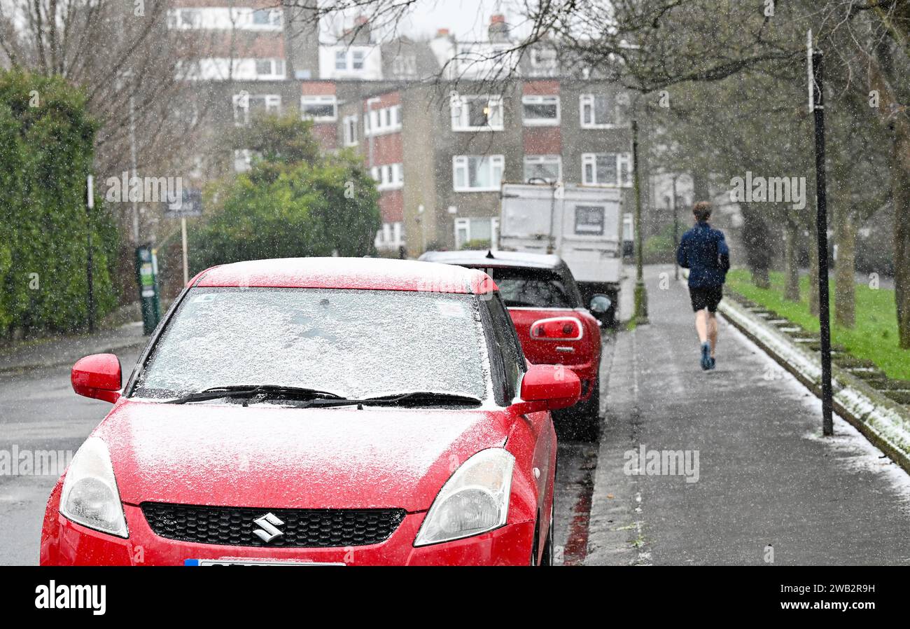 Brighton UK 8. Januar 2024 - Ein Läufer in Schnee und Schneeregen im Queens Park Brighton, als die Temperaturen nach dem jüngsten nassen Wetter und den Überschwemmungen in ganz Großbritannien sinken : Credit Simon Dack / Alamy Live News Stockfoto