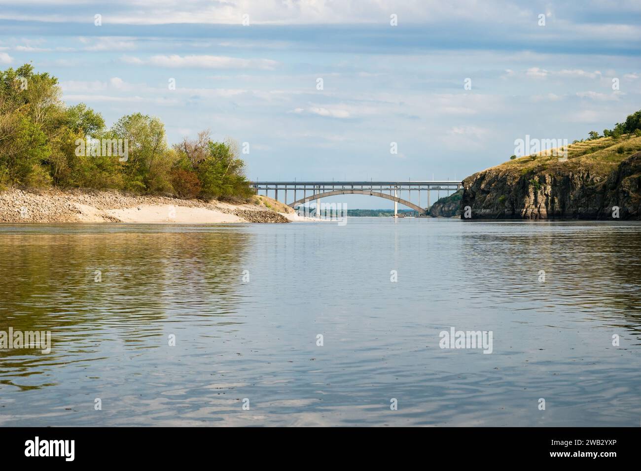 Bogenbrücke zwischen hohen felsigen Ufern eines breiten Flusses Stockfoto