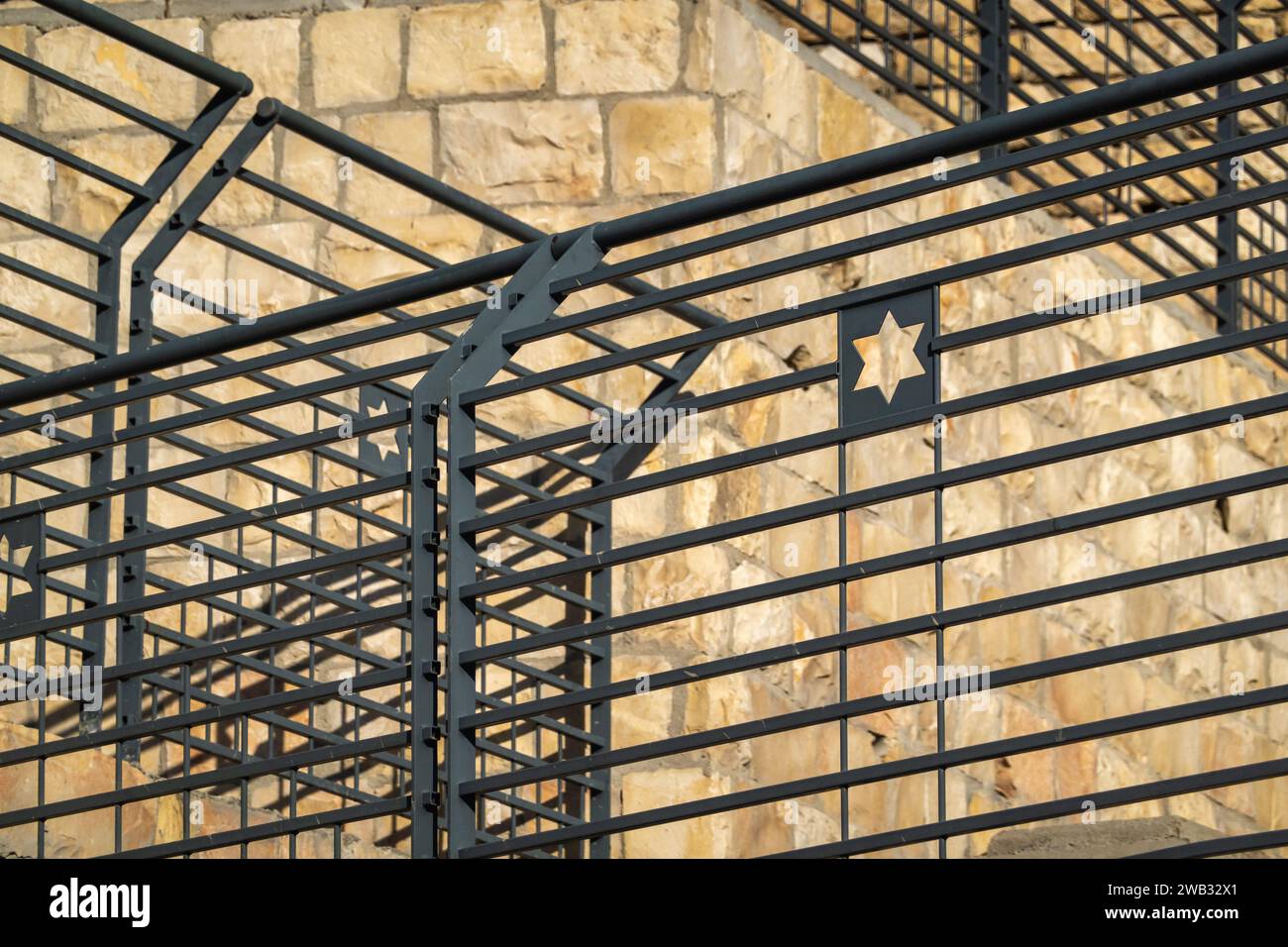 Fokussierte Ansicht eines Davidsterns, sichtbar auf einer Metallbarriere, die jüdische Identität vor einem Hintergrund aus veraltetem Stein symbolisiert Stockfoto