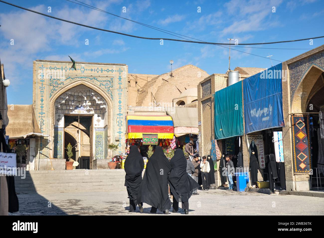 Rücken von drei in Tschador gekleideten Frauen vor dem Eingang der Jameh-Moschee von 771 n. Chr. und den Kuppeln des Großen Basars von Isfahan. Isfahan, Iran. Stockfoto