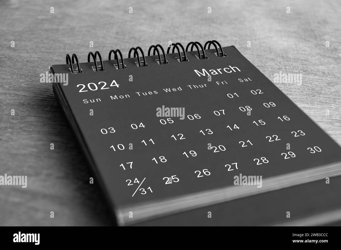 Schwarz-weißer Schreibtischkalender vom März 2024 auf Holzschreibtisch. Neues Monatskonzept Stockfoto