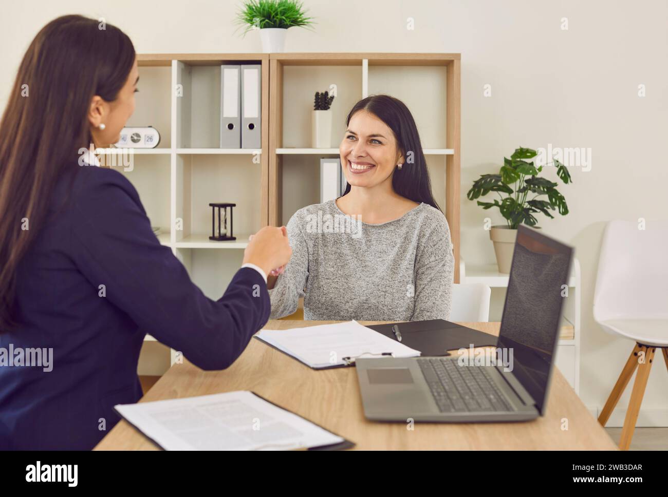 Zwei glückliche Frauen treffen sich im Büro, machen einen Geschäftsvertrag und tauschen Handshakes aus Stockfoto