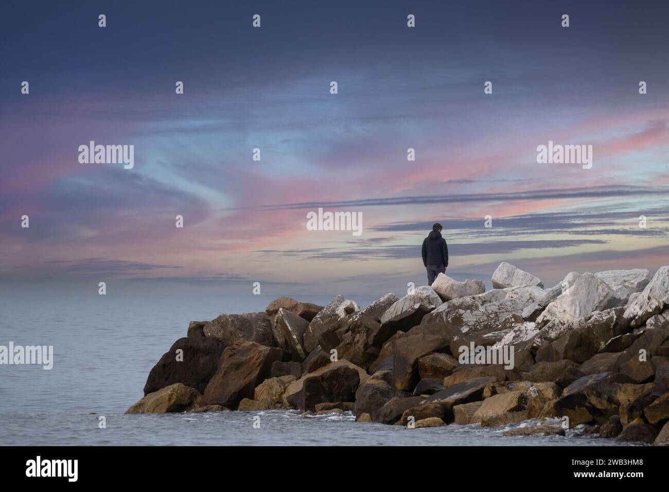 Junge, der auf den Klippen steht und das offene Meer bewundert, kontemplative Einsamkeit Stockfoto