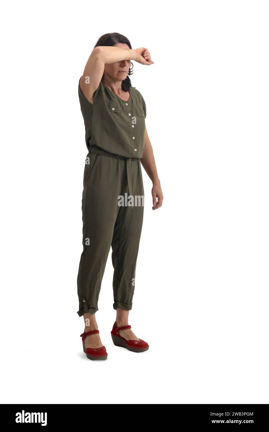 Frau, die ihr Gesicht mit ihrem Arm auf weißem Hintergrund bedeckt Stockfoto