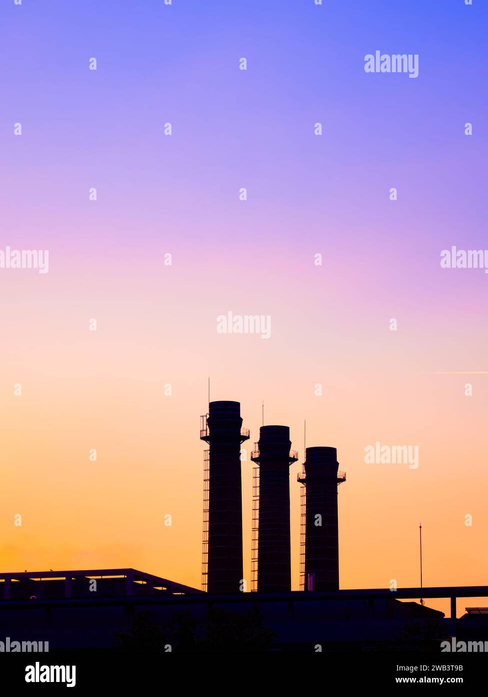 Drei industrielle Fabrikschornsteine bei Sonnenuntergang in Barcelona, Spanien Stockfoto