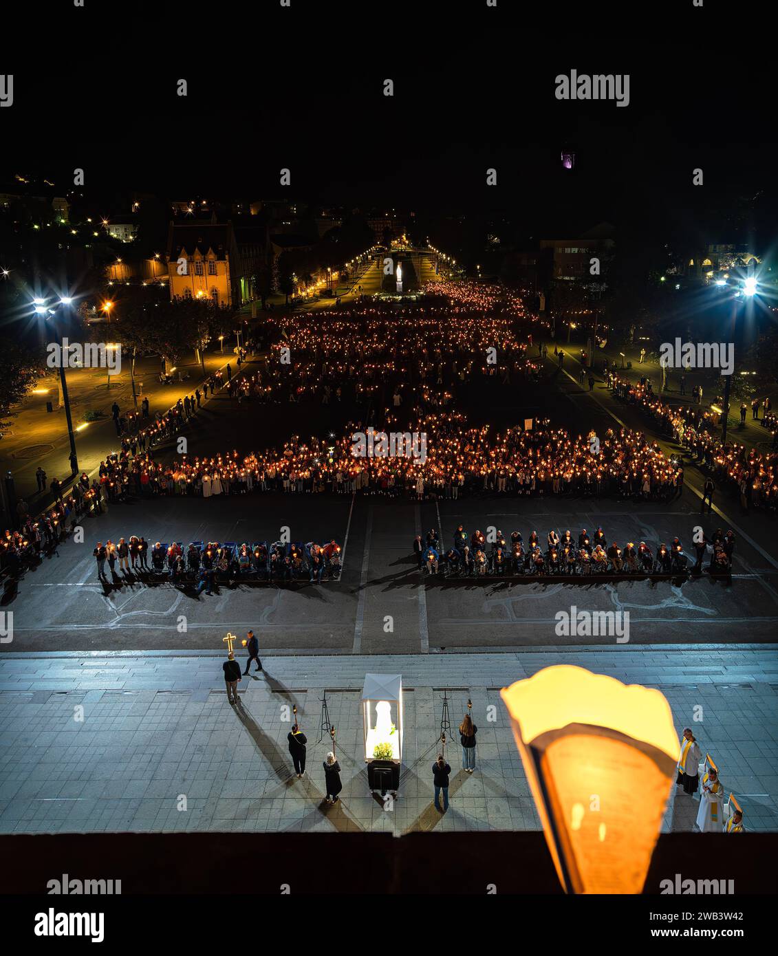 Lourdes, Frankreich - 12. Oktober 2023: Eine Pilgergruppe mit brennenden Kerzen betet bei einer nächtlichen Pilgerprozession in Lourdes. Stockfoto