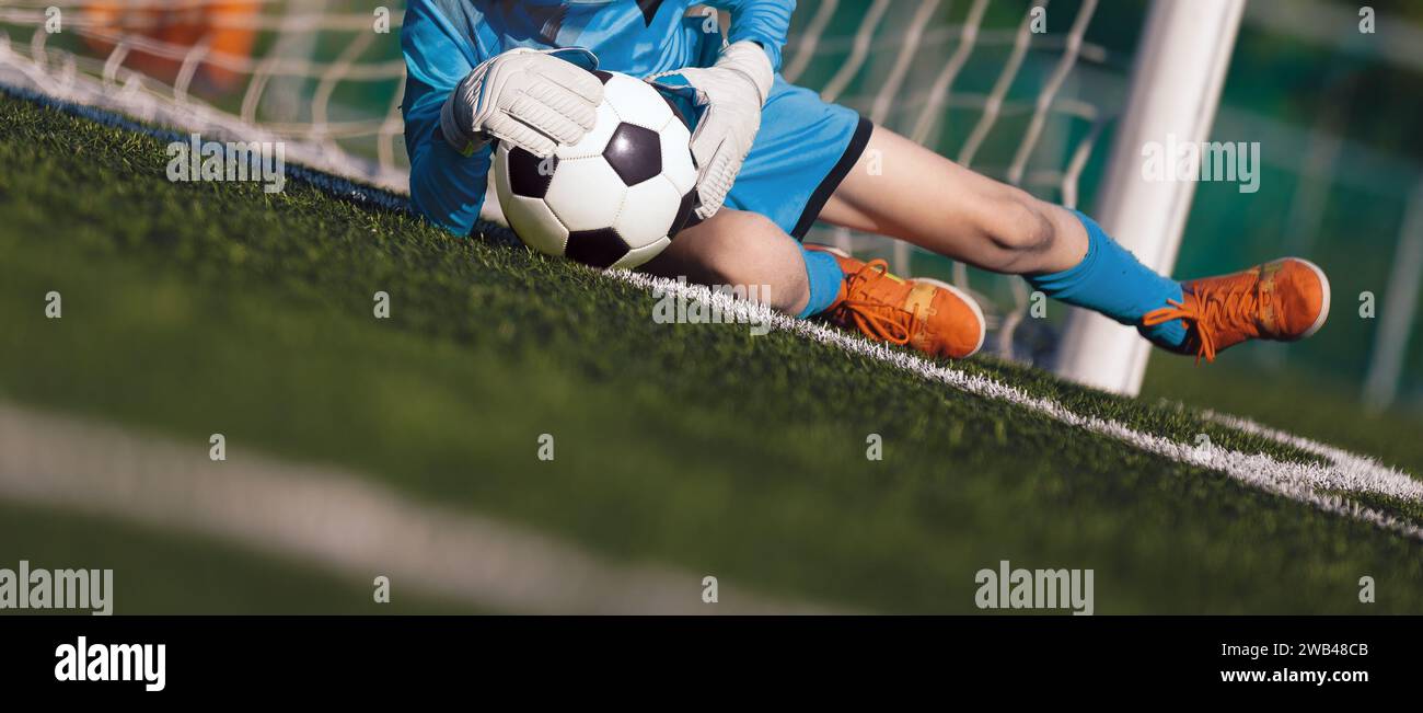 Junge als Fußballtorwart, der während eines Fußballspiels den Ball fängt. Fußballtorhüter in Trikot und Sporthandschuhen spielen ein Fußballturnier Stockfoto