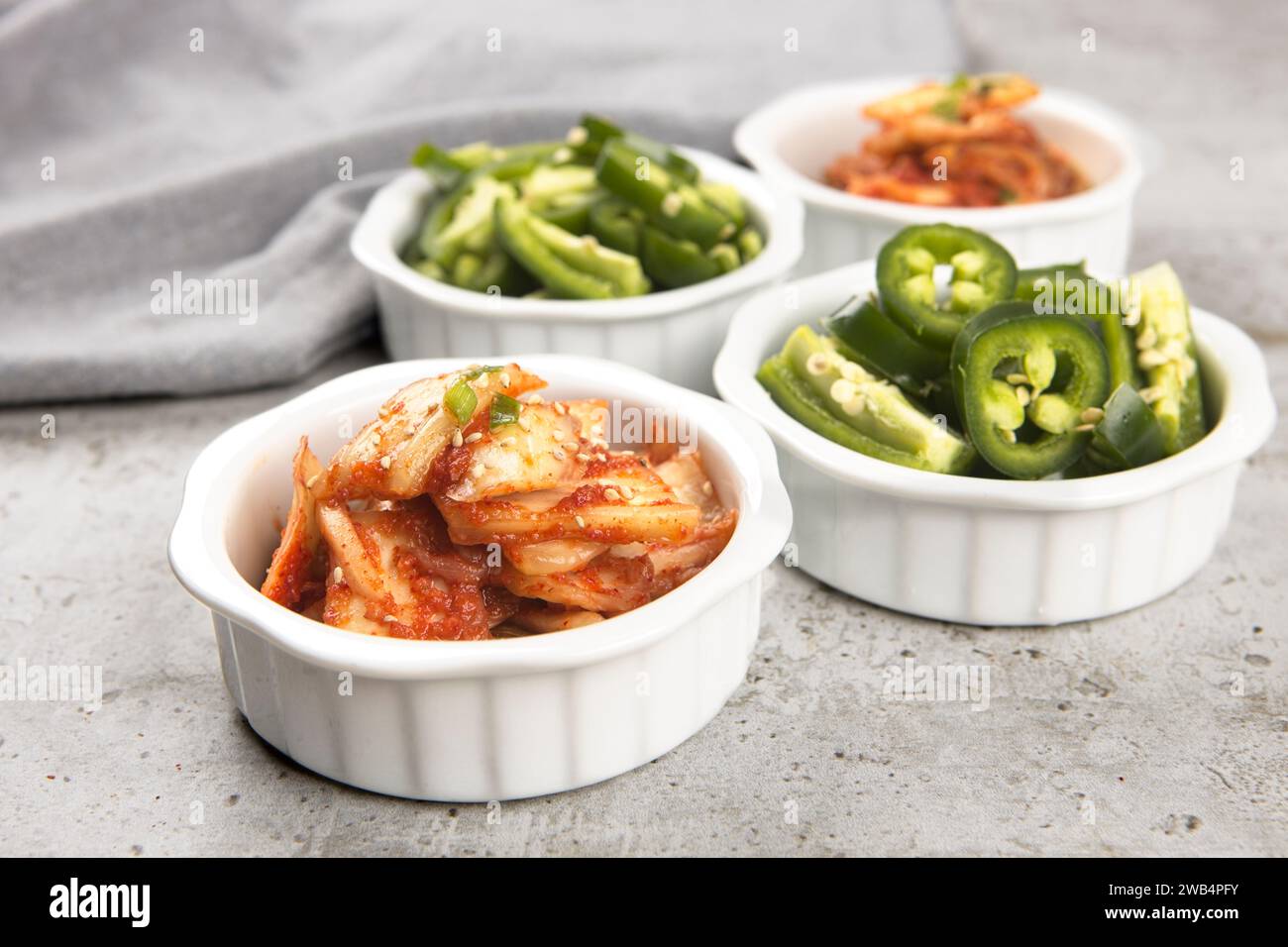 Ein Nahaufnahme-Foto von Schüsseln koreanischer Kimchi und in Scheiben geschnittener Jalapeno-Paprika. Stockfoto