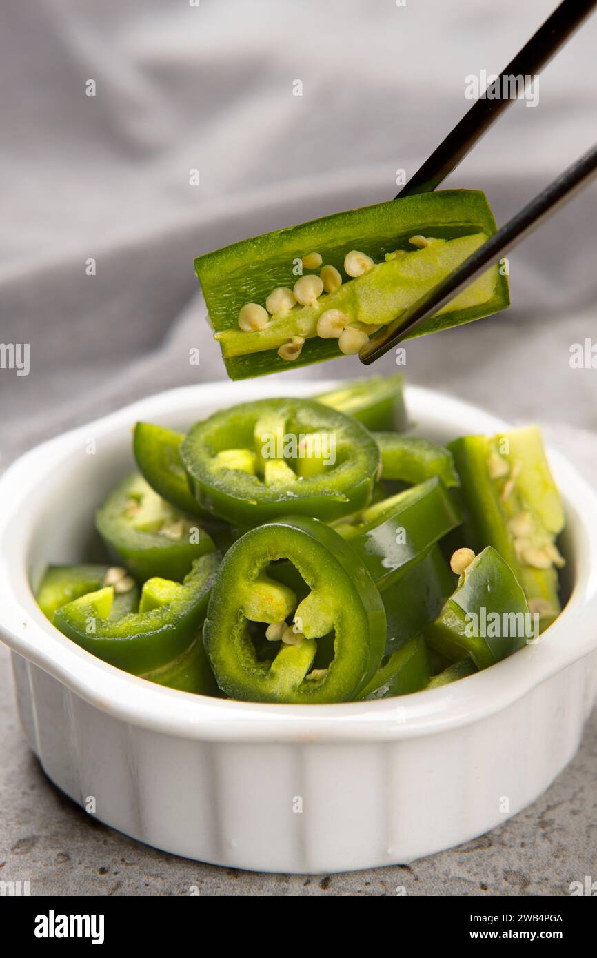 Ein Lebensmittelfoto von einer Schüssel mit geschnittenen Paprika und einem Paar Essstäbchen, die eine Scheibe durchbohren. Stockfoto