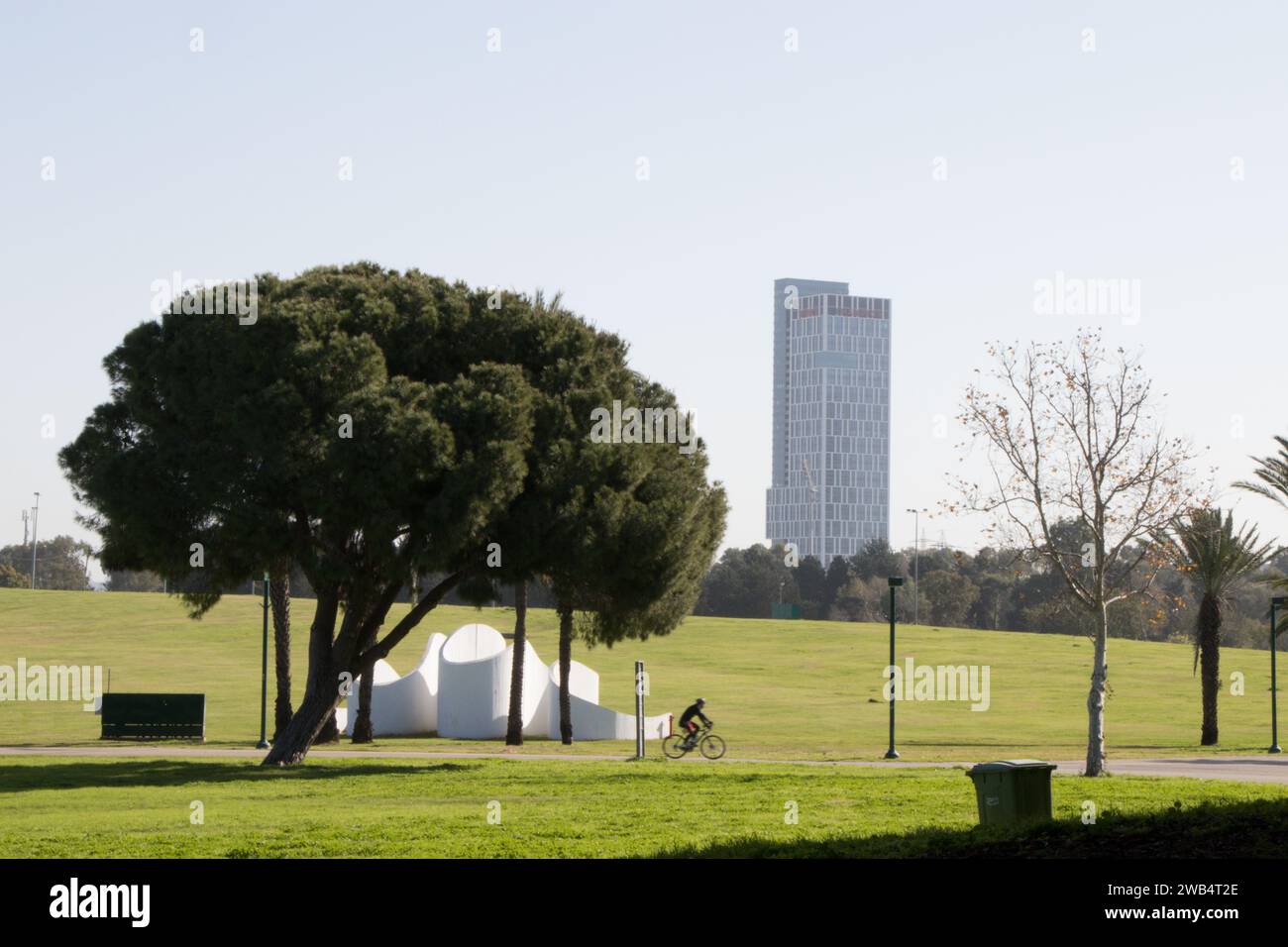 Ein großer Park im Stadtzentrum mit breiten grünen Rasenflächen, Fahrrad-, Wander- und Joggingwegen. Im Hintergrund befinden sich die Bürotürme der Stadt. Stockfoto